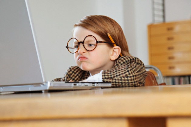 bimba di cativo umore guarda il computer con gli occhiali da grande e una matita sull'orecchio